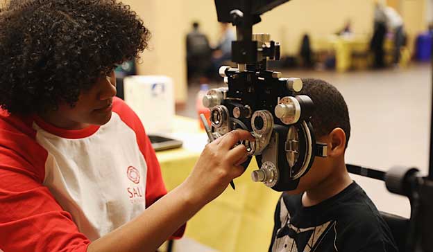 Give Help Charities Image of an eye care profession completing an eye exam on a child